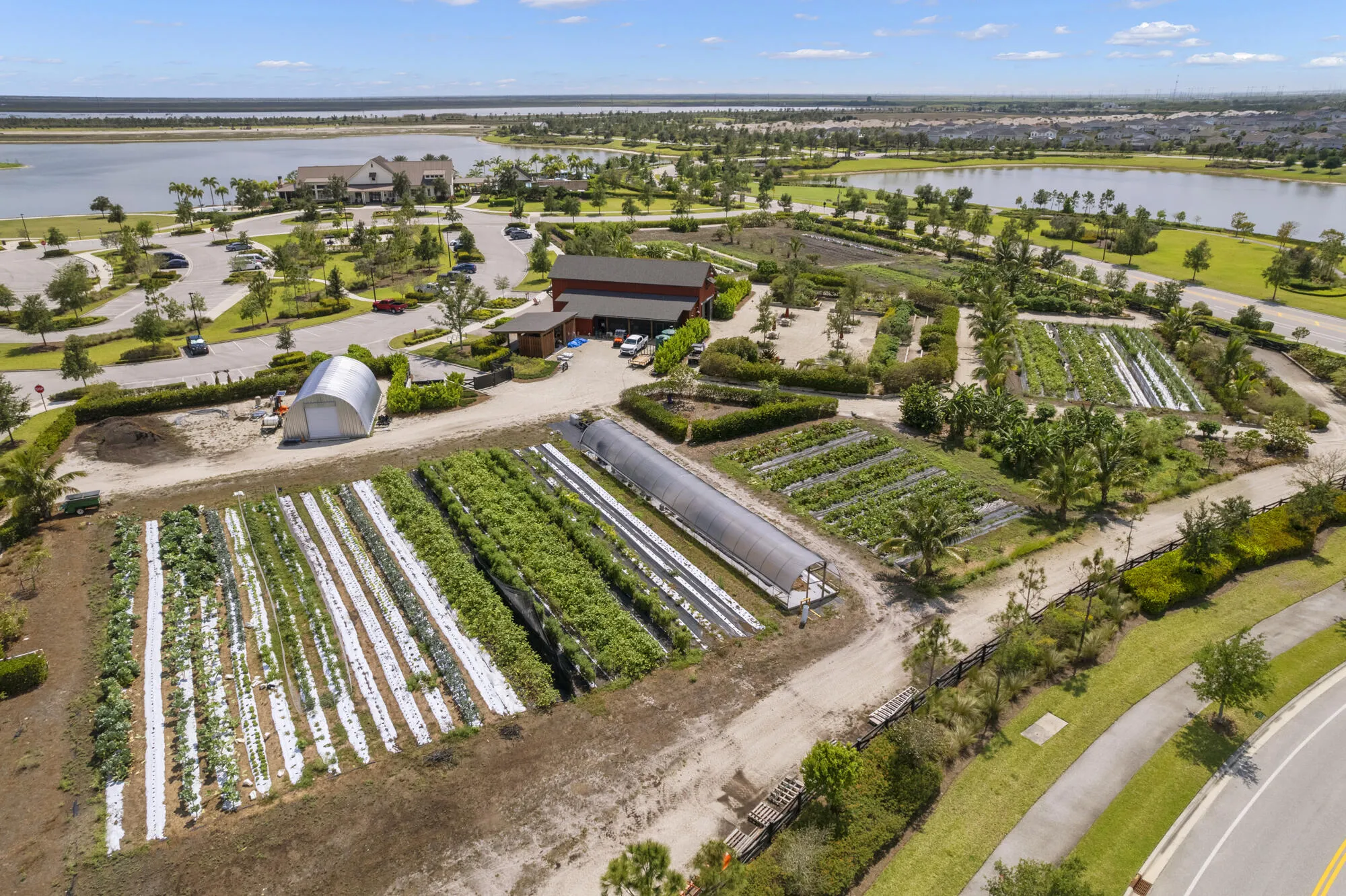 Expansive farm featuring multiple cultivated fields and two hoop houses