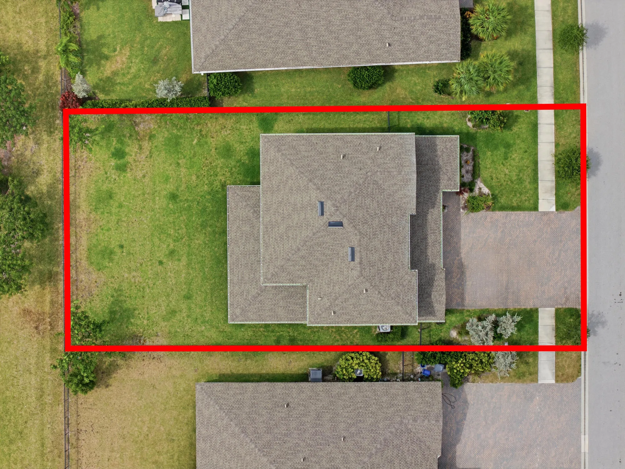 Aerial property view featuring a light-colored shingle roof and a paved driveway