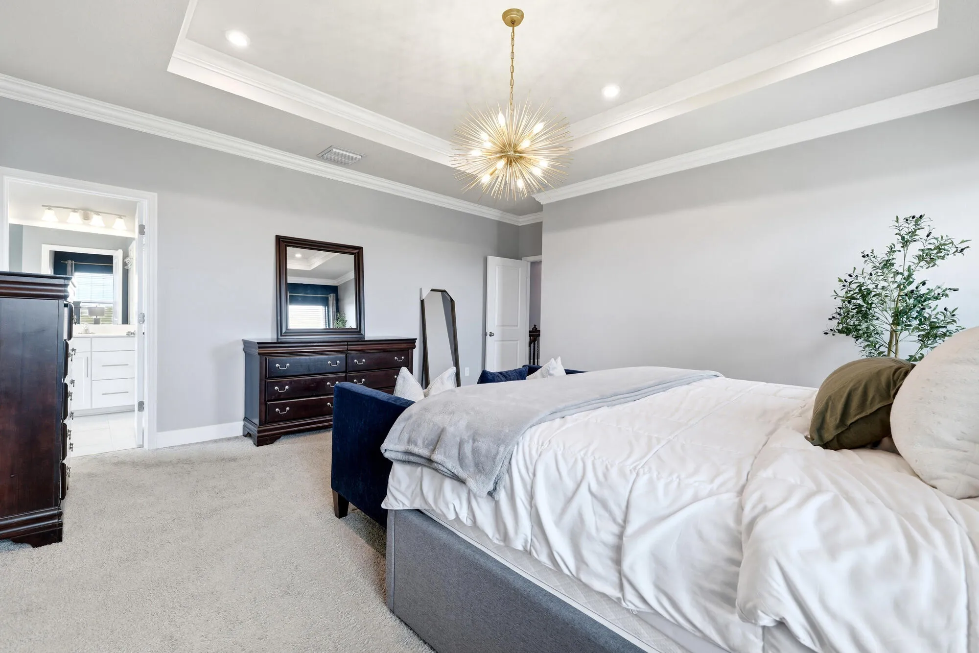 Spacious primary suite featuring a tray ceiling with recessed lighting and a central chandelier