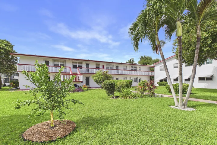 White stucco building with red trim accents and multiple private balconies