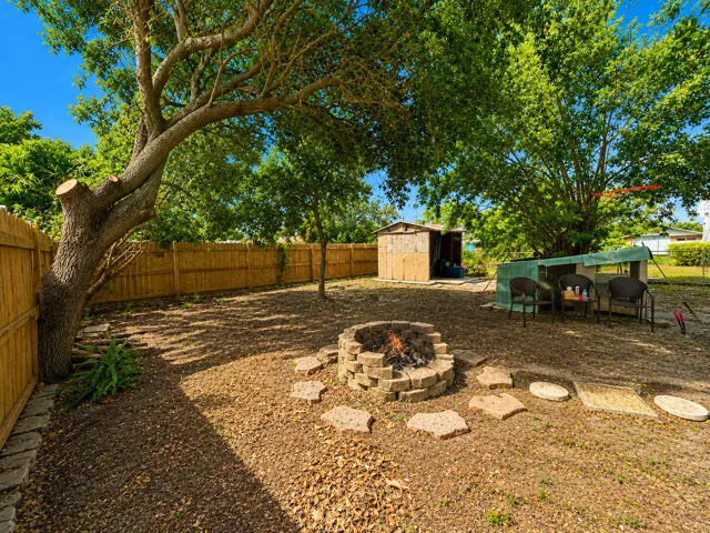 Circular stone fire pit surrounded by a stepping-stone path, framed by lush landscaping