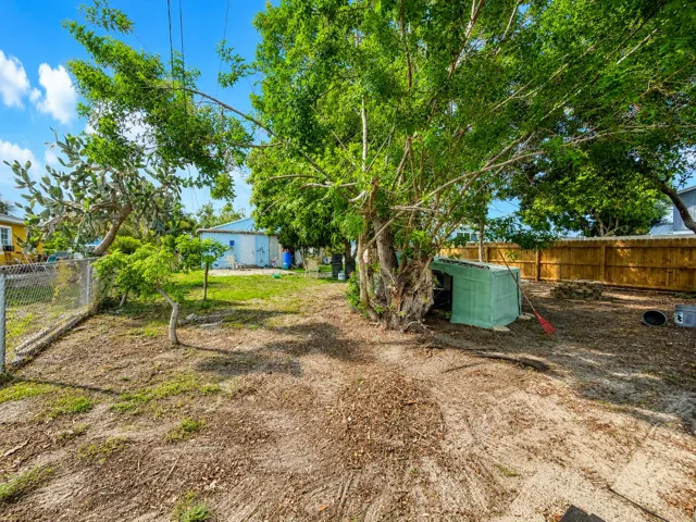 Expansive backyard with mature trees, chain-link side fencing, and a chicken coop tucked under the canopy