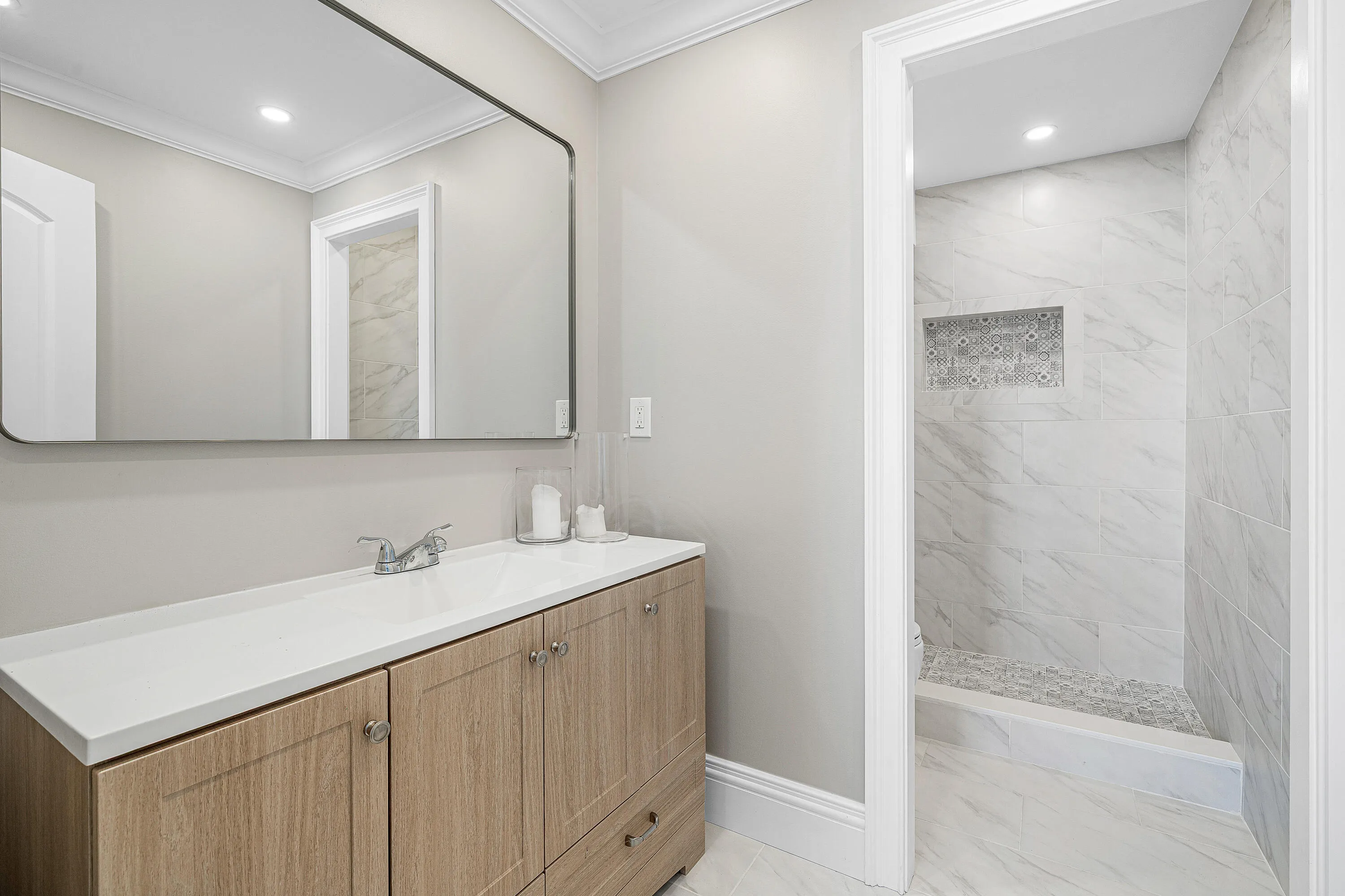 Spa-inspired primary bathroom featuring a floating wood-finish vanity with an expansive white quartz countertop, polished nickel fixtures, and an illuminated mirror