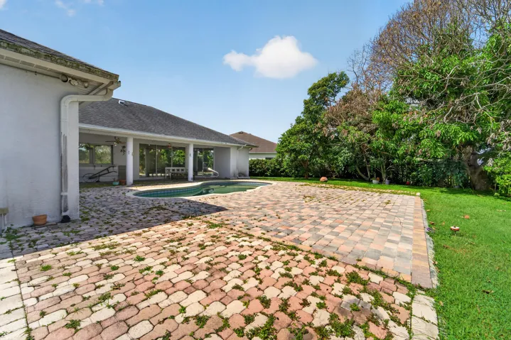 Paved patio area, curved in-ground pool, covered patio, lush green lawn, mature trees