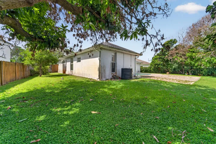Expansive grassy lawn with a wood plank privacy fence and mature trees