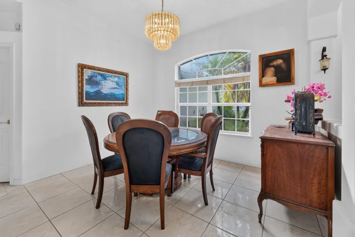 Large arched window with grid detailing, tile flooring, and a decorative chandelier