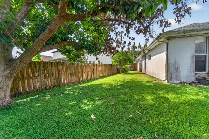 Expansive grassy yard with a mature tree and a wood privacy fence