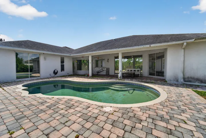 Kidney-shaped swimming pool with integrated steps, surrounded by a paver patio