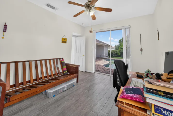 Bright, open living space featuring wood-finish flooring, a ceiling fan with integrated lighting, and sliding glass doors opening to outdoor space
