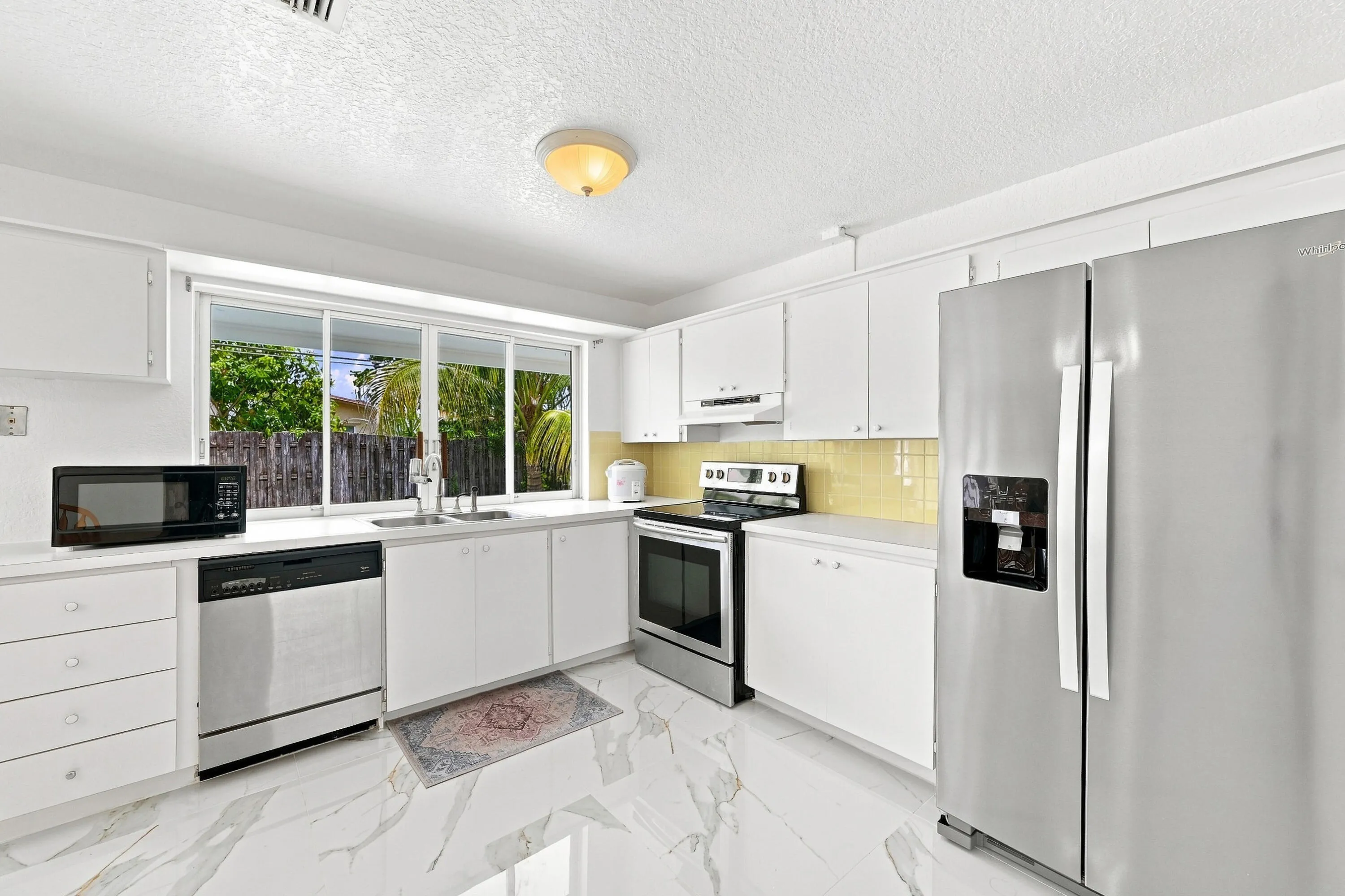 Modern kitchen featuring white cabinetry, stainless steel appliances including a side-by-side refrigerator, a range, and a dishwasher