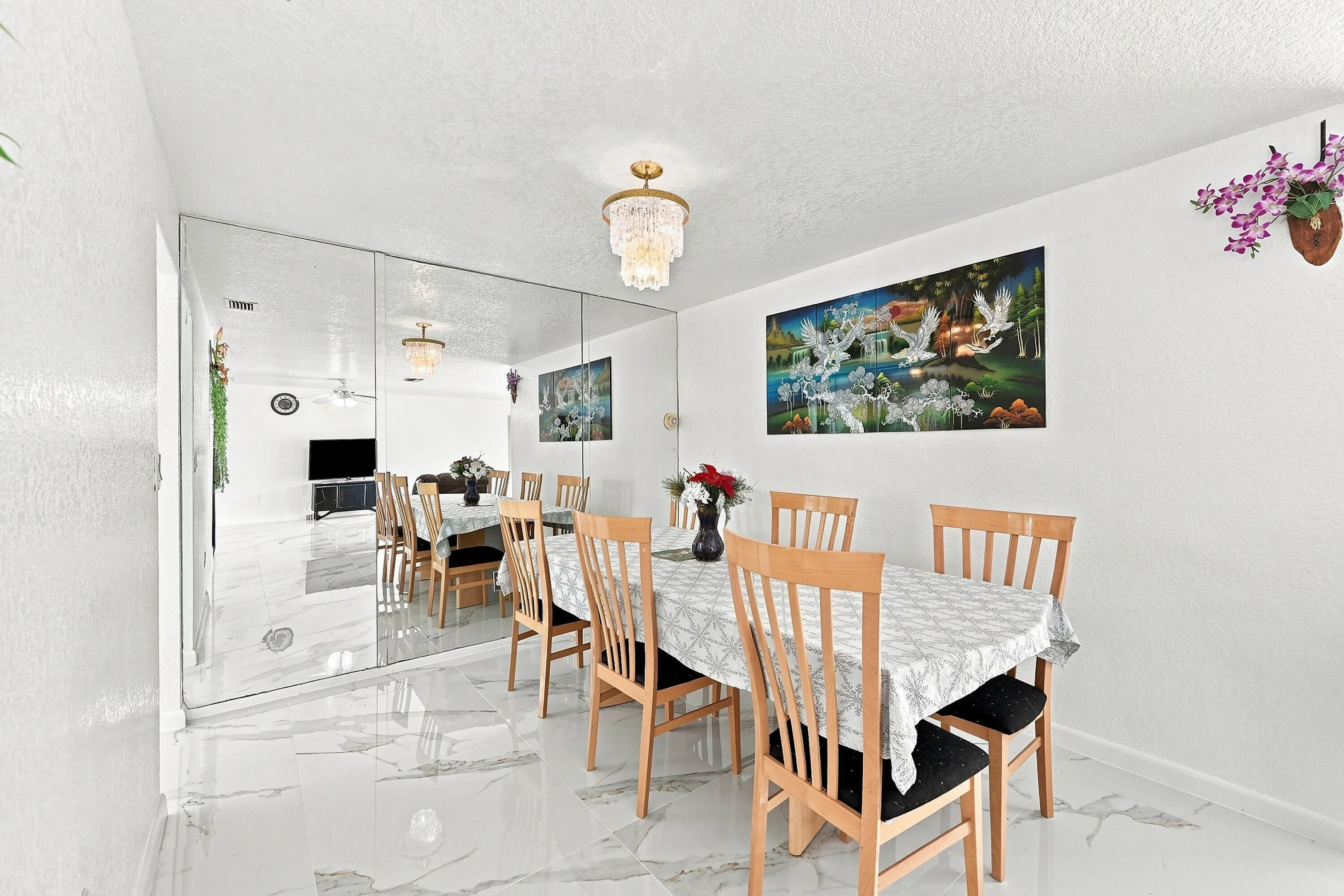 Dining space featuring a mirrored accent wall, white walls, and a contemporary chandelier