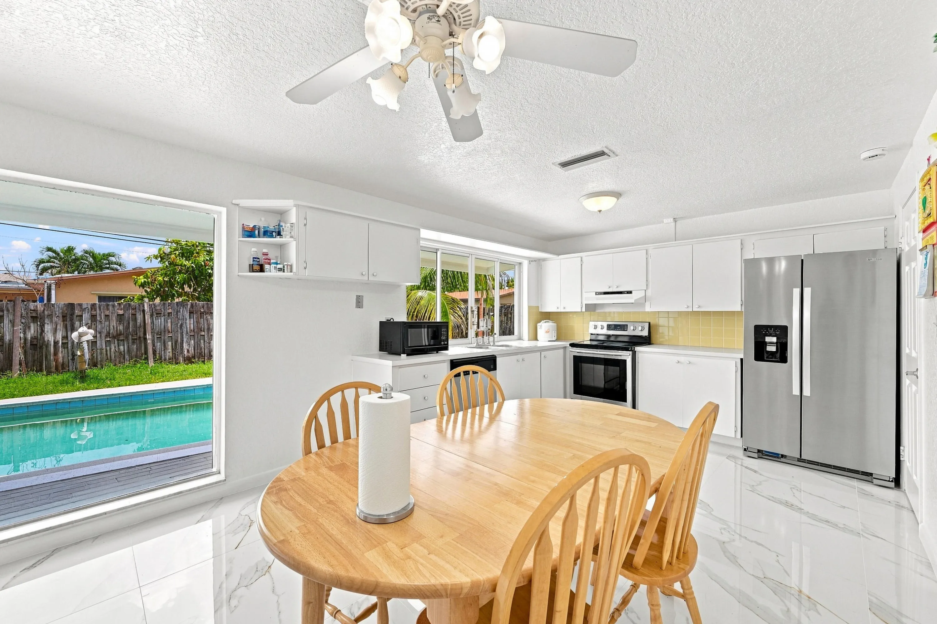 Kitchen with white cabinetry, stainless steel appliances, and a light yellow subway tile backsplash