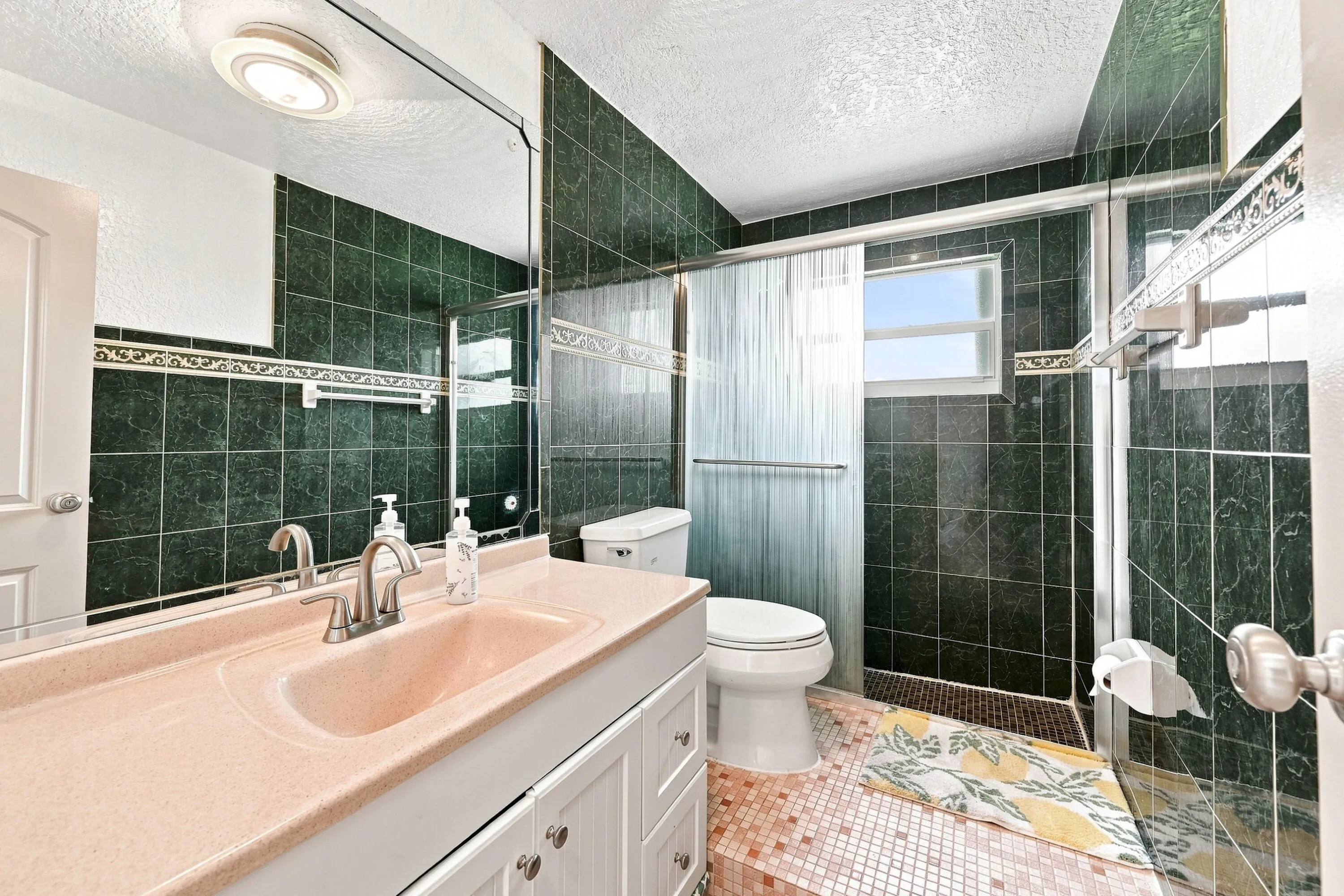 primary bathroom featuring vanity with quartz countertop and undermount sink, designer green tile surround, walk-in shower with frameless glass enclosure