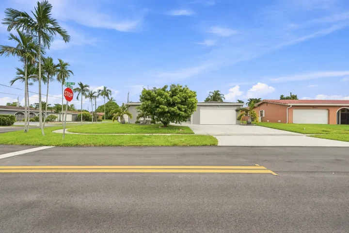Single-story residence featuring a two-car garage, concrete driveway, and a front lawn with mature landscaping