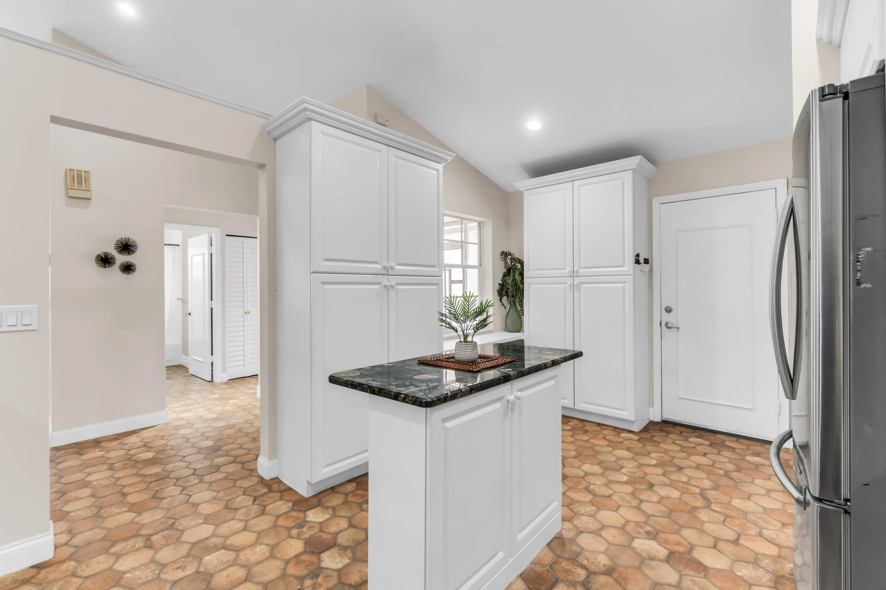 Kitchen featuring a central island with a dark stone countertop, white shaker-style cabinetry, and hexagonal tile flooring