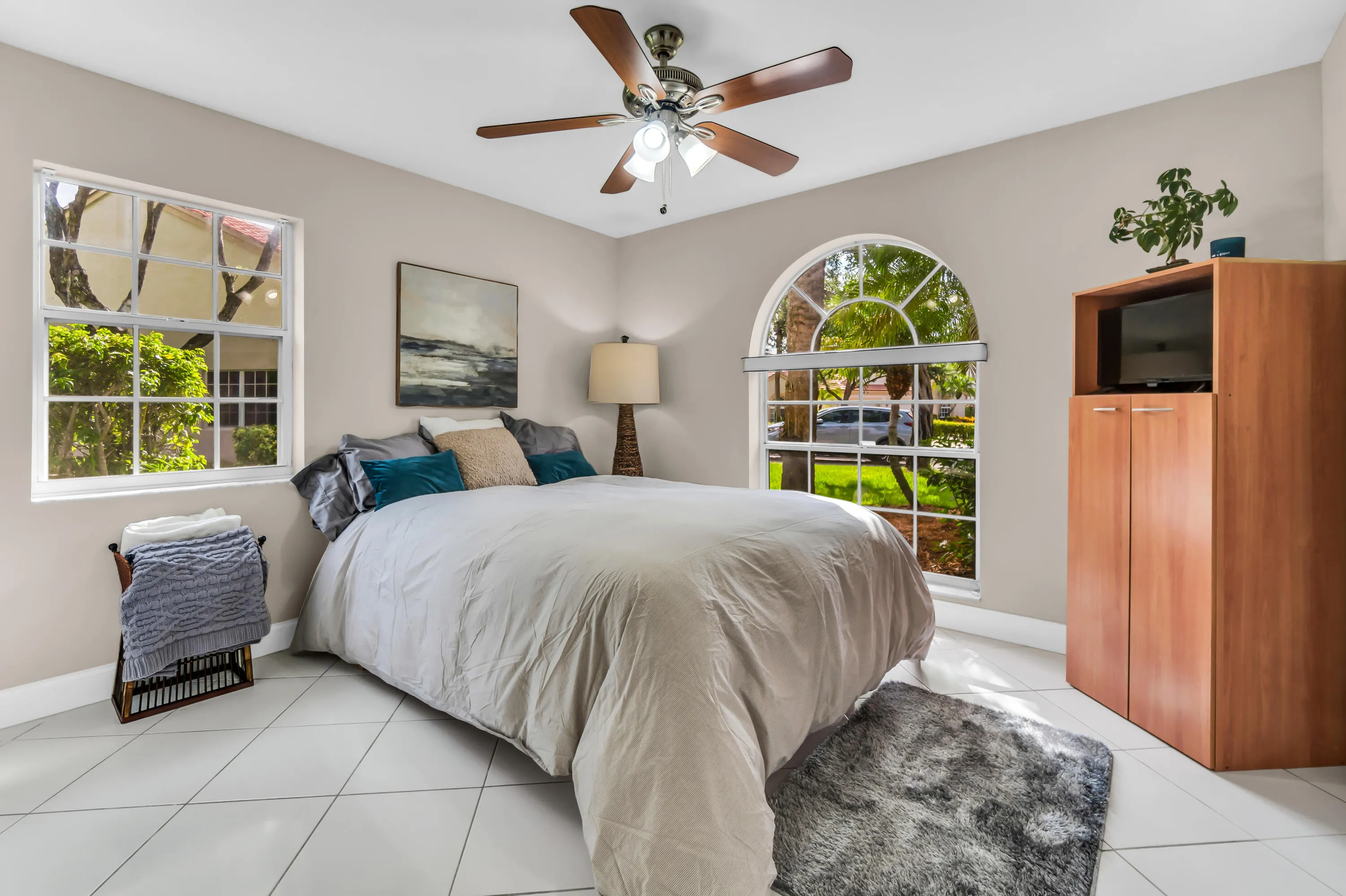 Bedroom featuring white square tile flooring, neutral wall tones, and a ceiling fan with light fixture