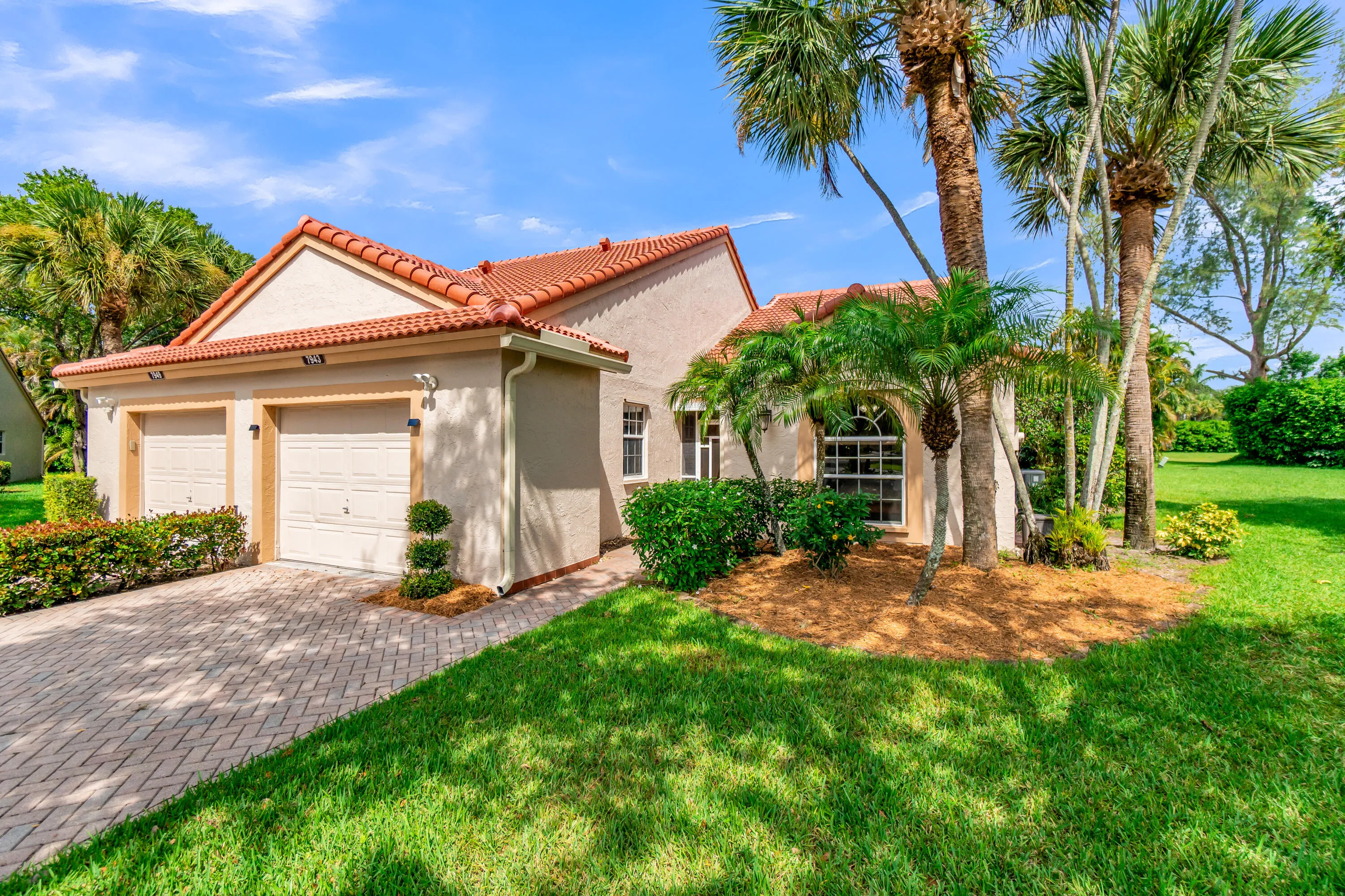 Stucco exterior featuring a red tile roof, two-car garage, and a paver driveway