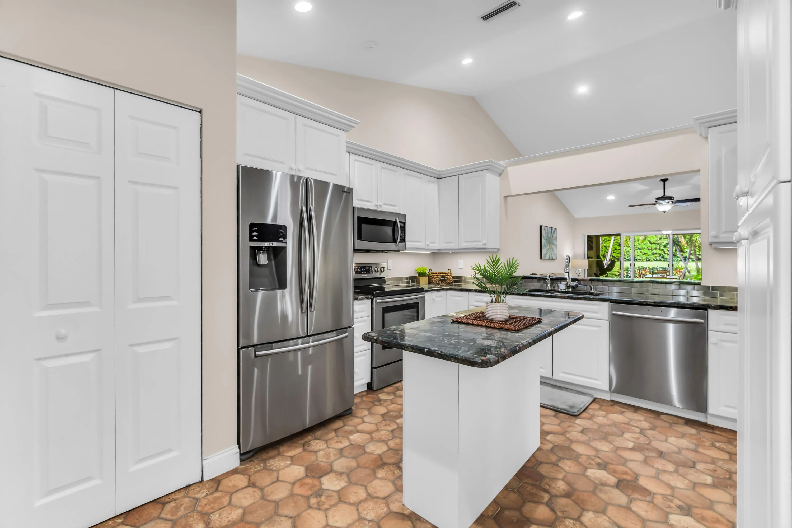 Kitchen featuring white cabinetry, stainless steel appliances, a center island with a dark countertop, and unique hexagonal flooring