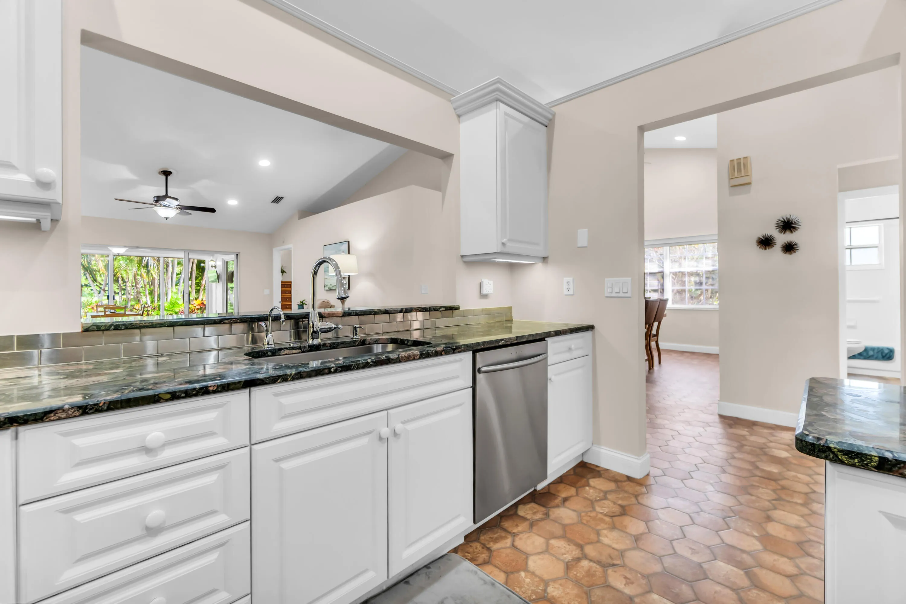 Kitchen featuring white cabinetry, dark granite countertops, stainless steel appliances, and a tile backsplash