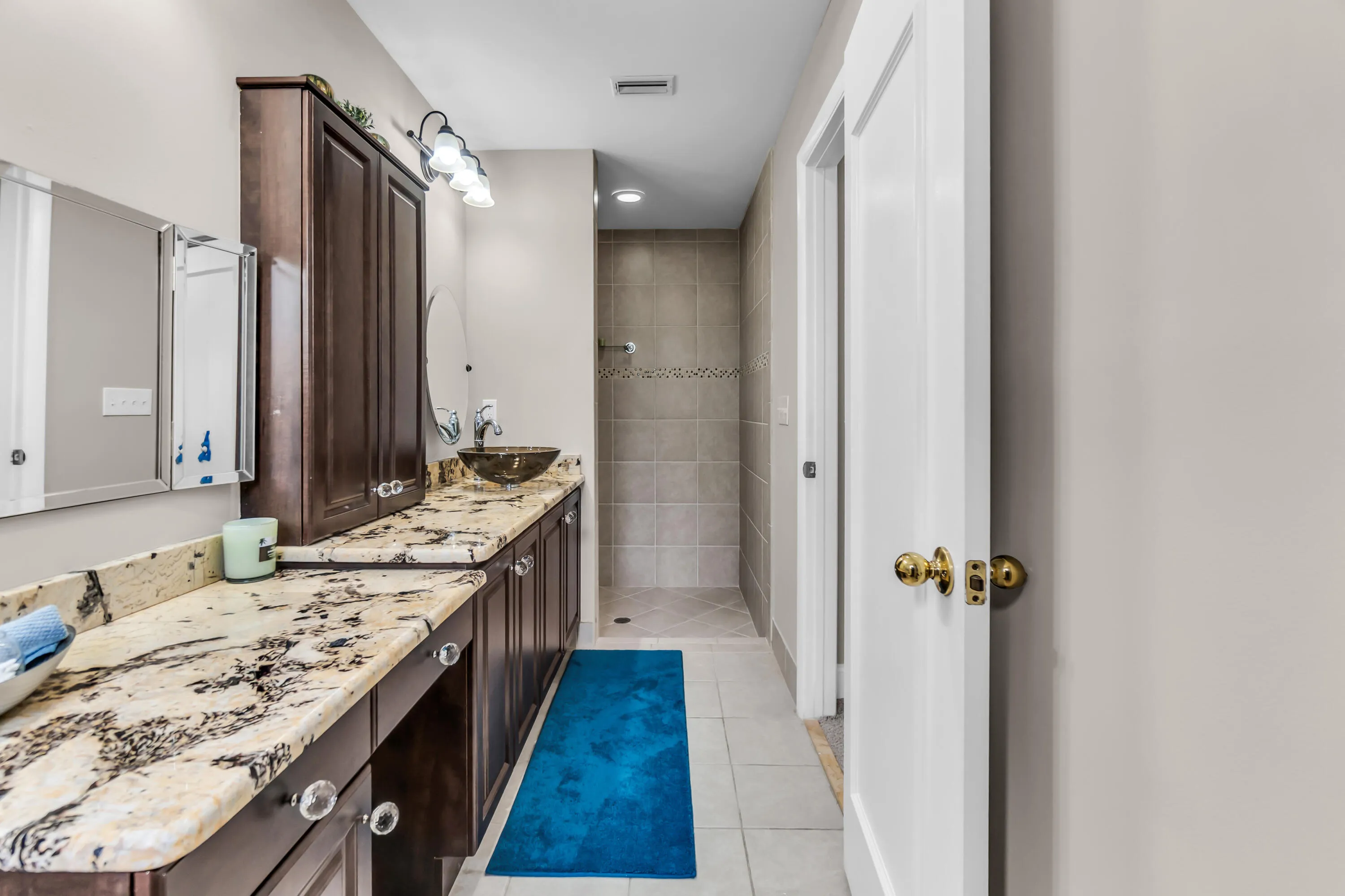 Bathroom featuring an extended vanity with stone countertops, a vessel sink, and an integrated shower