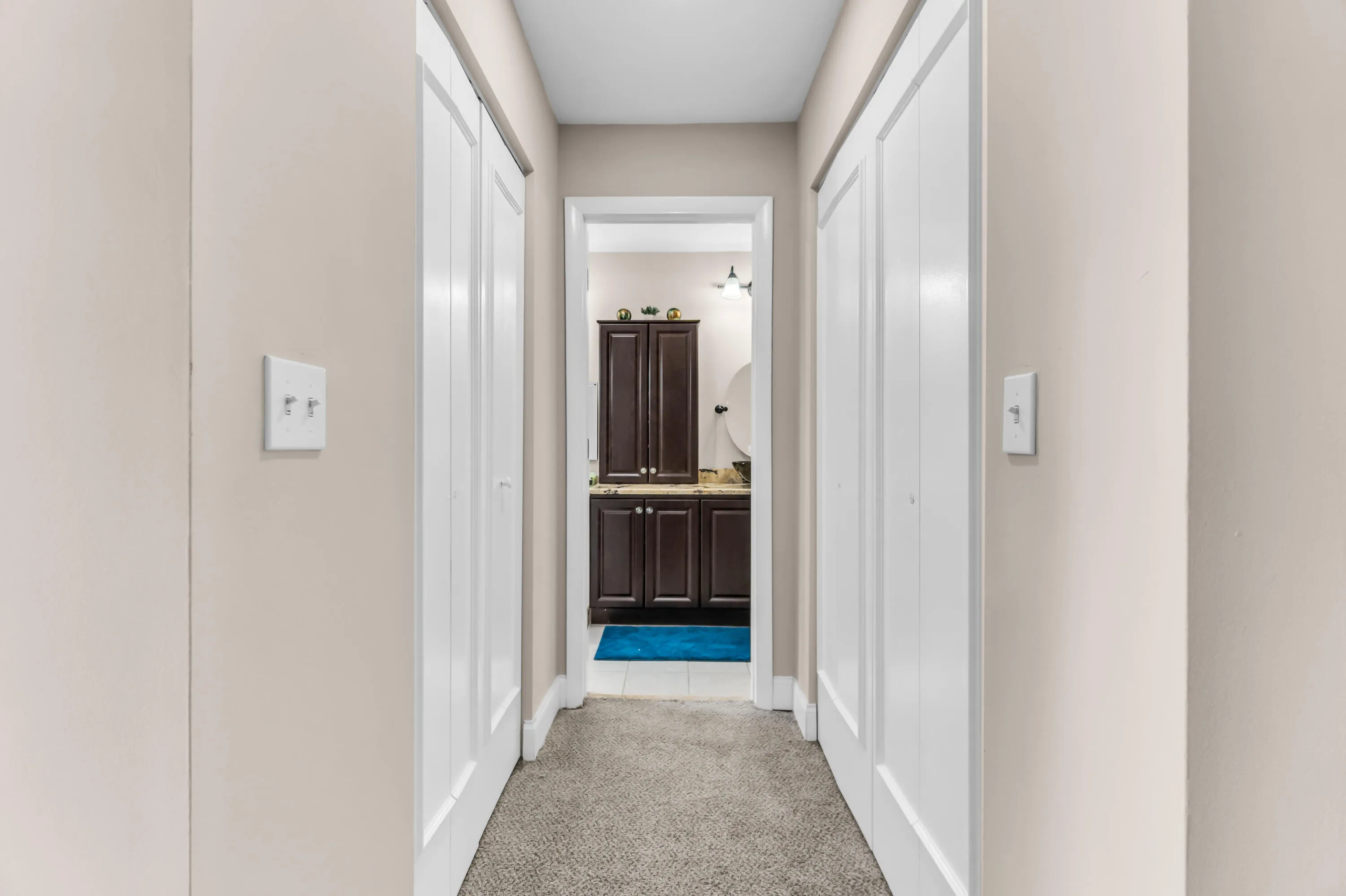 Carpeted hallway with light neutral walls and white bi-fold doors