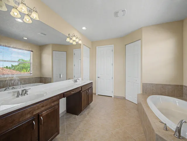 Dual vanity with integrated sinks, dark wood-finish cabinetry, and expansive wall mirror