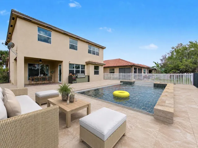 Expansive rear patio featuring a built-in swimming pool, integrated spa, and extensive tile decking