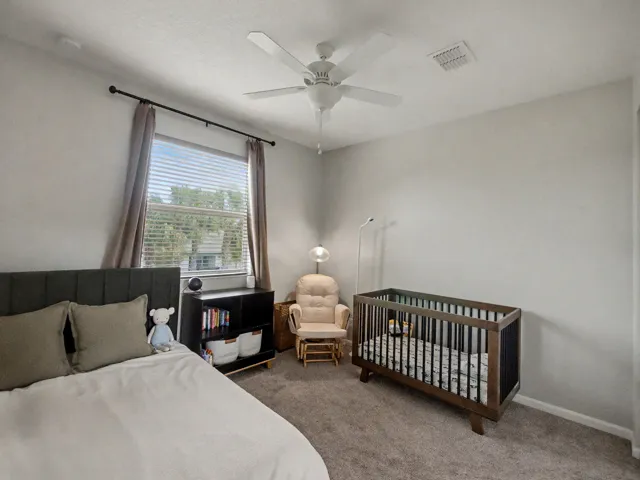 Carpeted room featuring a ceiling fan, a window with blinds, and a built-in shelving unit