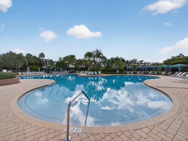 Expansive freeform swimming pool with integrated steps, surrounded by paver decking