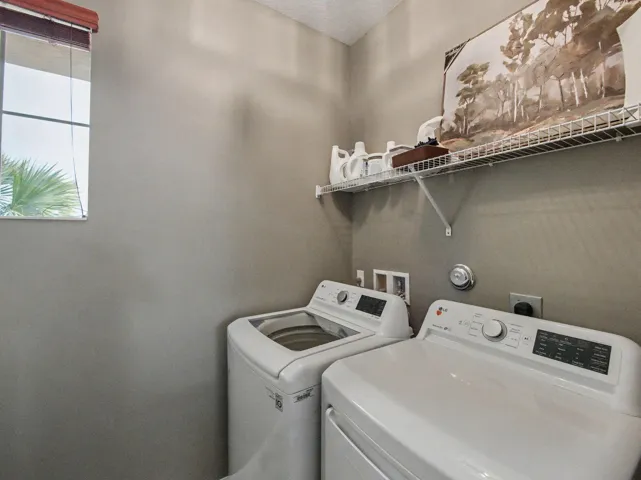 Utility area featuring a window, wire shelving, and appliance connections