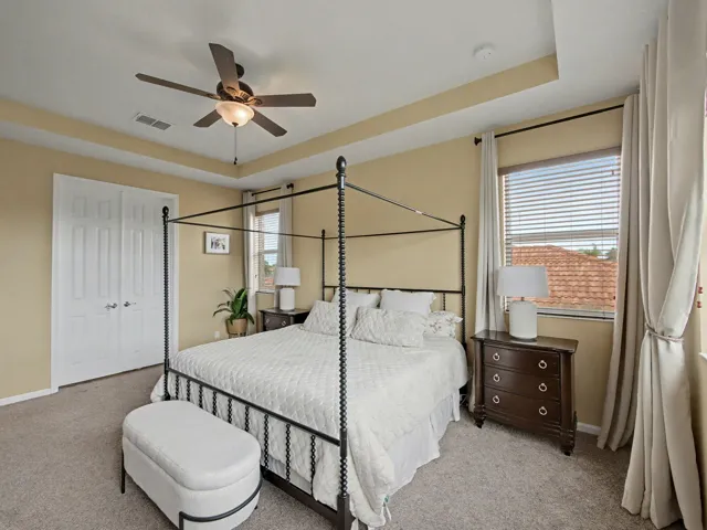 Tray ceiling, ceiling fan with light, bi-fold closet doors, window with blinds, and carpeted flooring
