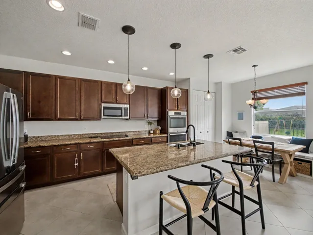 Kitchen featuring a large central island, dark wood cabinetry, granite countertops, and stainless steel appliances