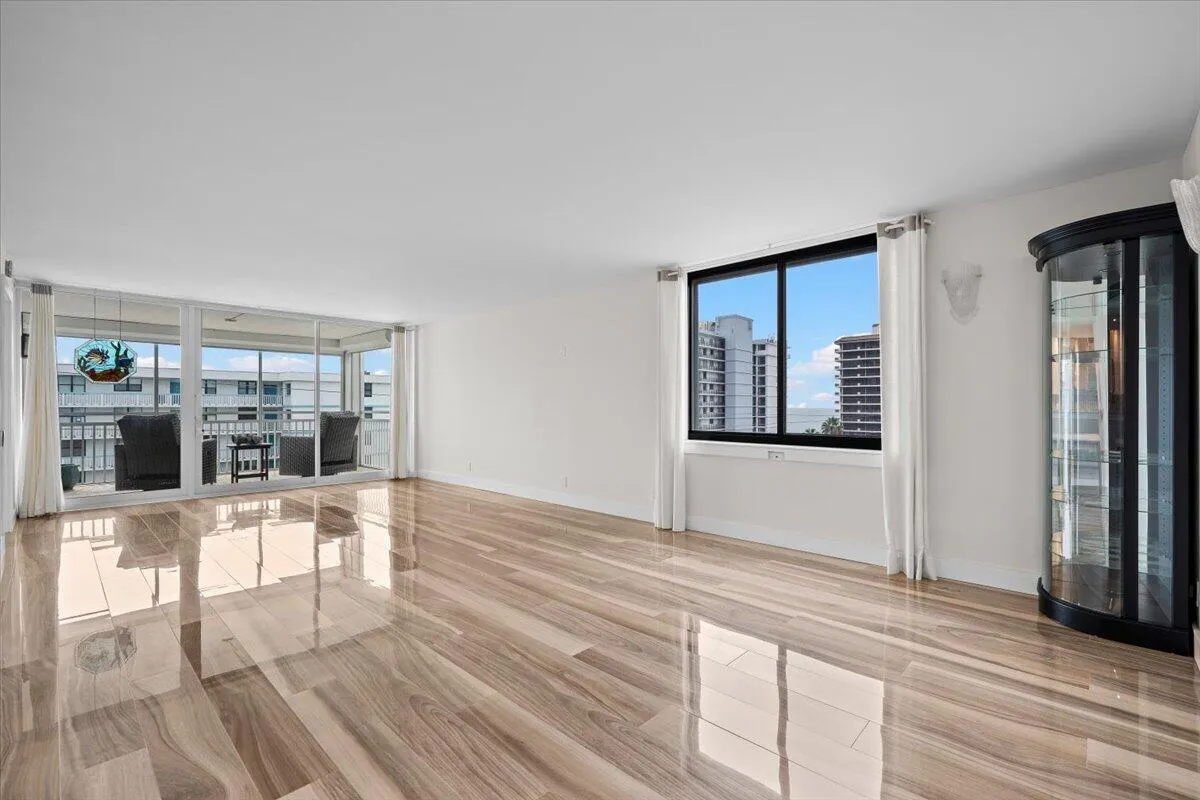 Expansive interior with glossy wood-finish flooring, white walls, and a built-in display cabinet
