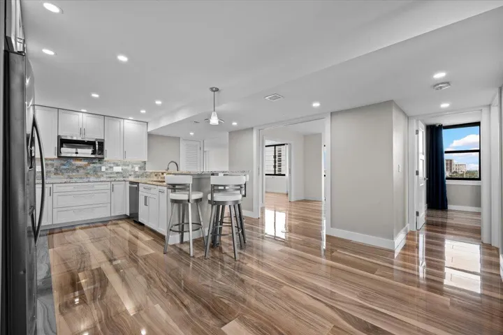 Spacious kitchen featuring white cabinetry, a stone countertop, and wood-finish flooring