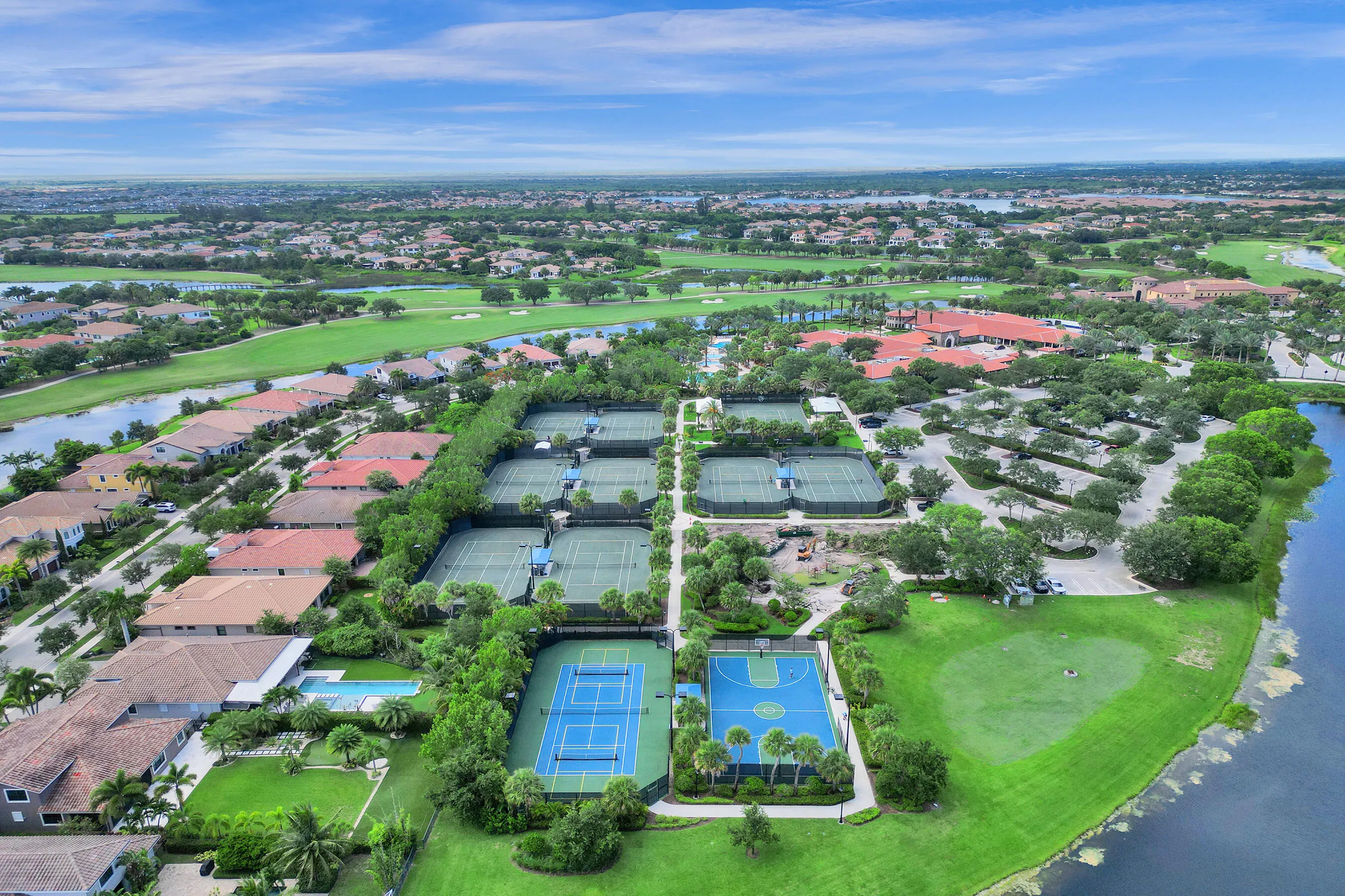 Community amenities featuring multiple tennis courts, a basketball court, golf greens, and a clubhouse structure