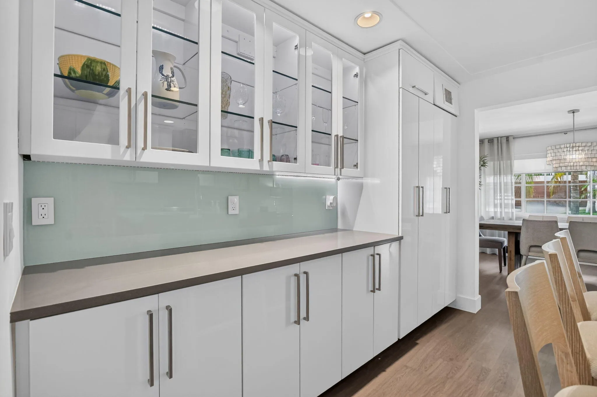 Beautiful illuminated glass cabinets, the under cabinet lighting design provides a unique glow against the custom designed backsplash. Take a look at all of the counter space in this kitchen.
