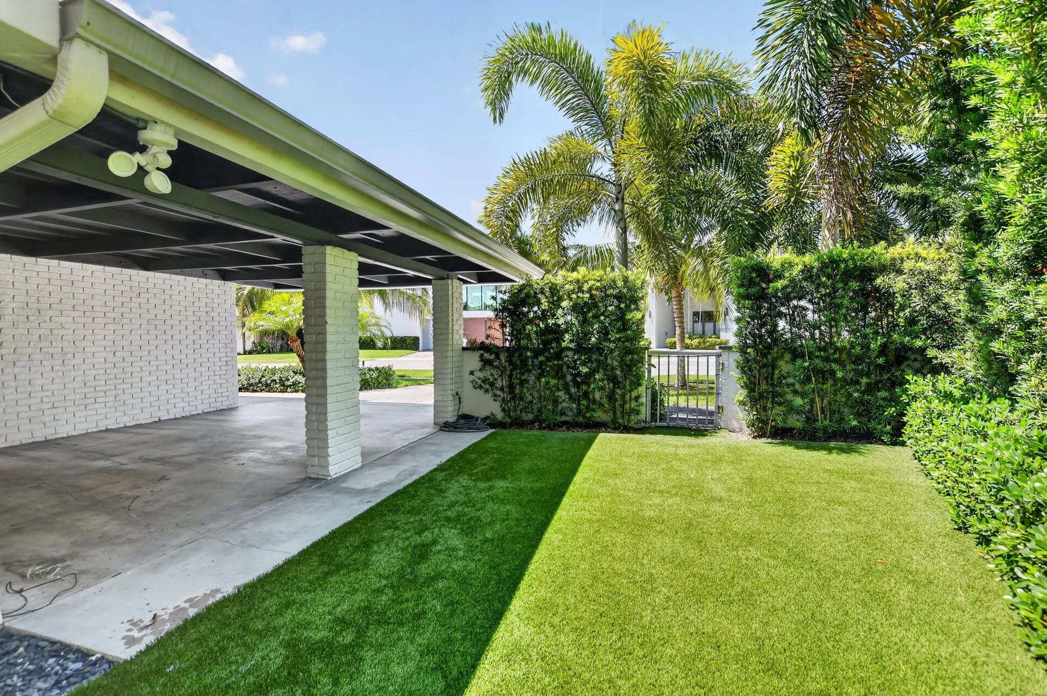This is the West side elevation of the Carport, the yard is partially fenced in . The side and rear yards have recently installed artificial turf, no need for a mower, sprinklers, or fertilizer! Safe for children and pets too!