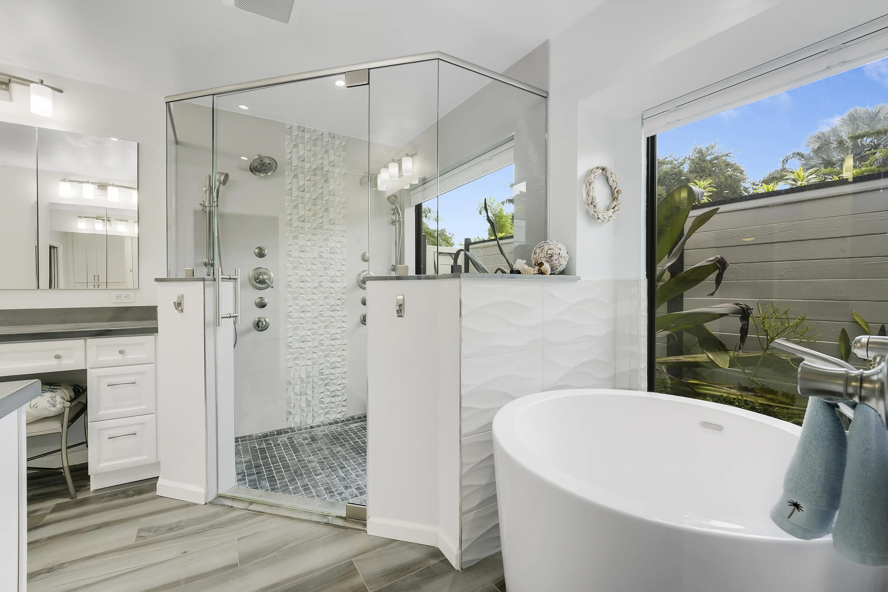 Bright and modern bath featuring a freestanding soaking tub, large window with serene views, and contemporary finishes.