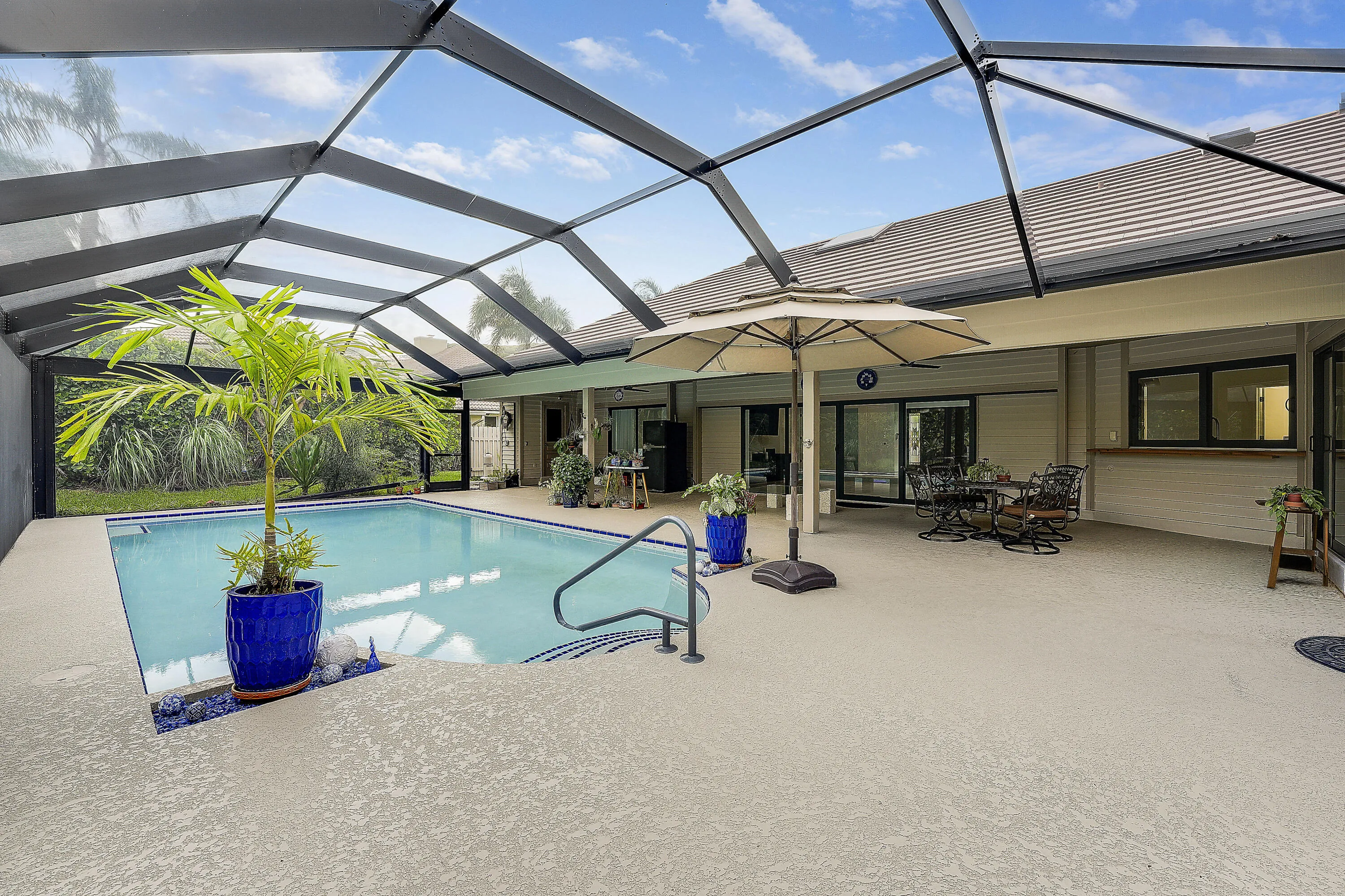 Beautiful screenedin pool area with upgraded deck, tropical landscaping, and a heated saltwater pool, perfect for year-round outdoor living.