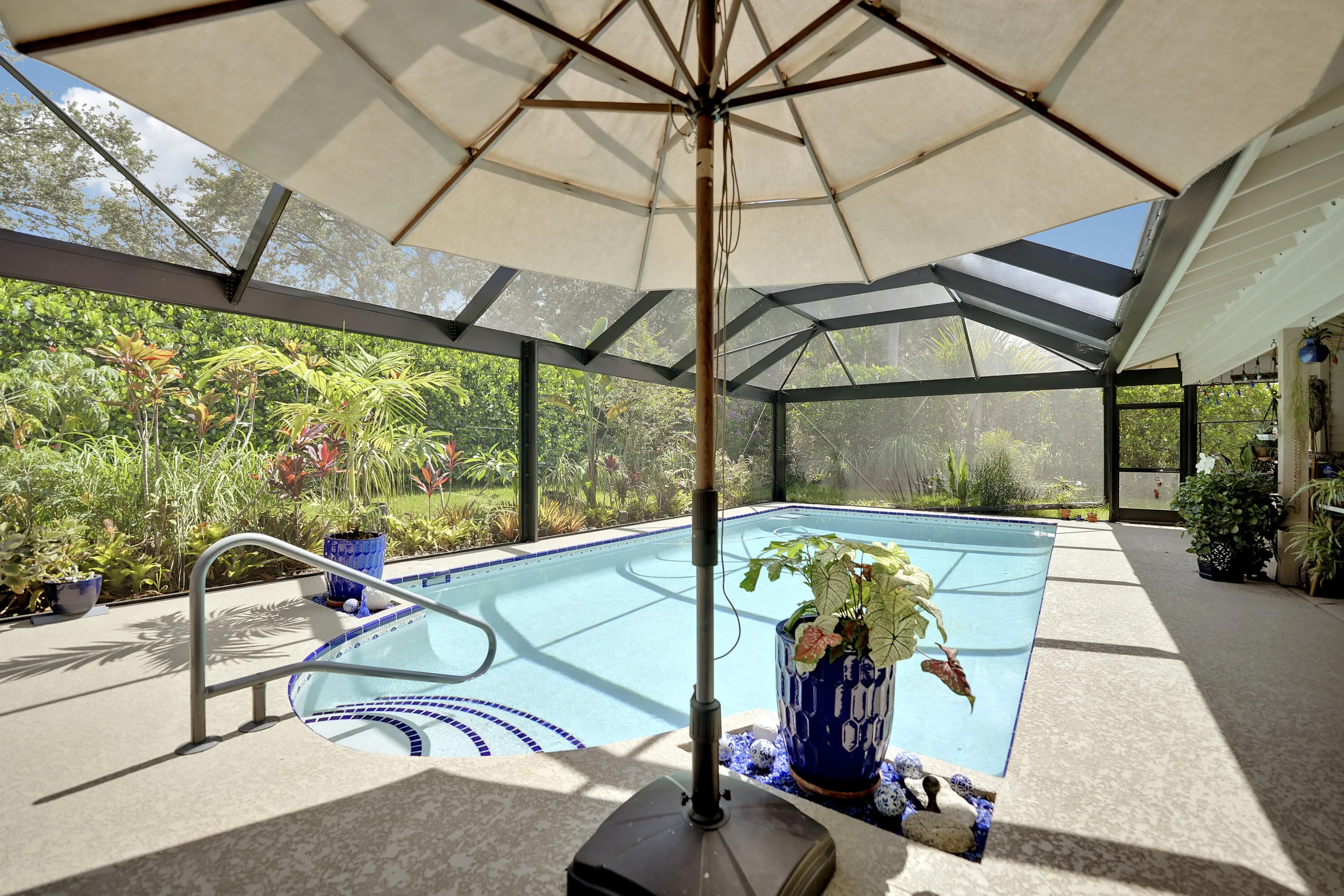 Beautiful screened in pool area with upgraded deck, tropical landscaping, and a heated saltwater pool, perfect for year-round outdoor living.
