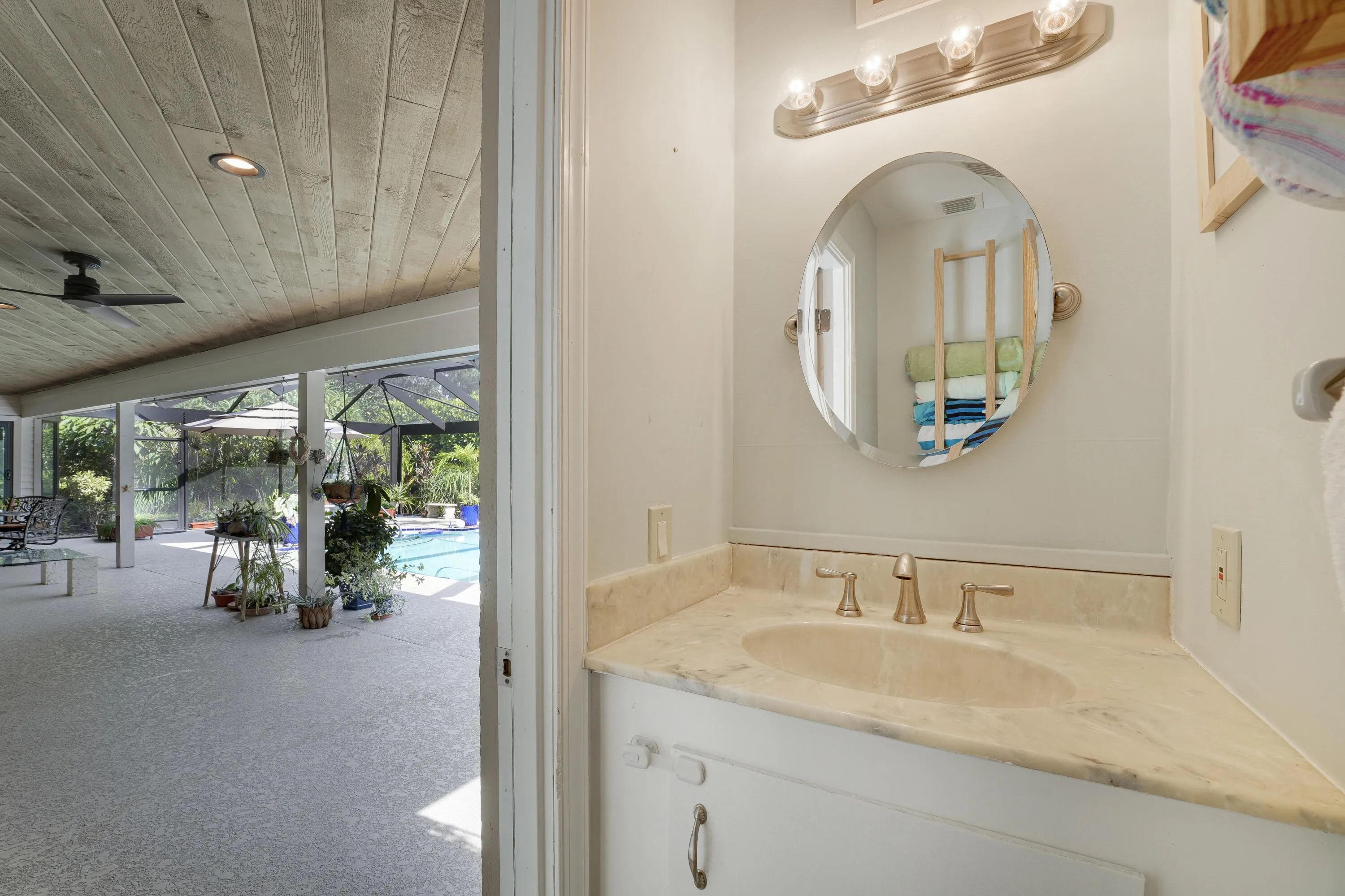 Convenient air-conditioned half bath with modern vanity and direct access to the lanai and screened pool — perfect for outdoor entertaining.