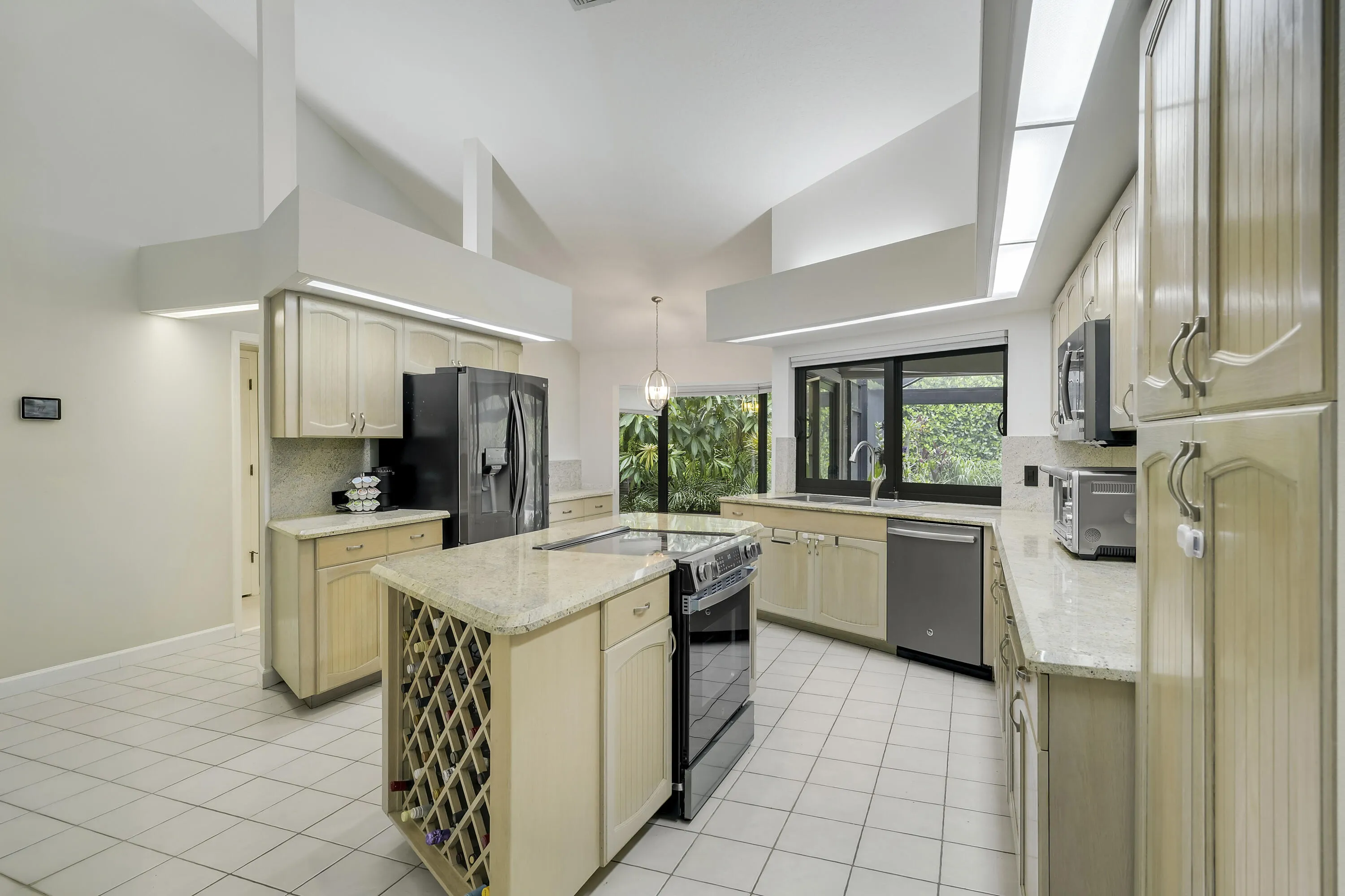 Contemporary kitchen with high ceilings, recessed lighting, stainless appliances, and a central island with builtin wine storage.