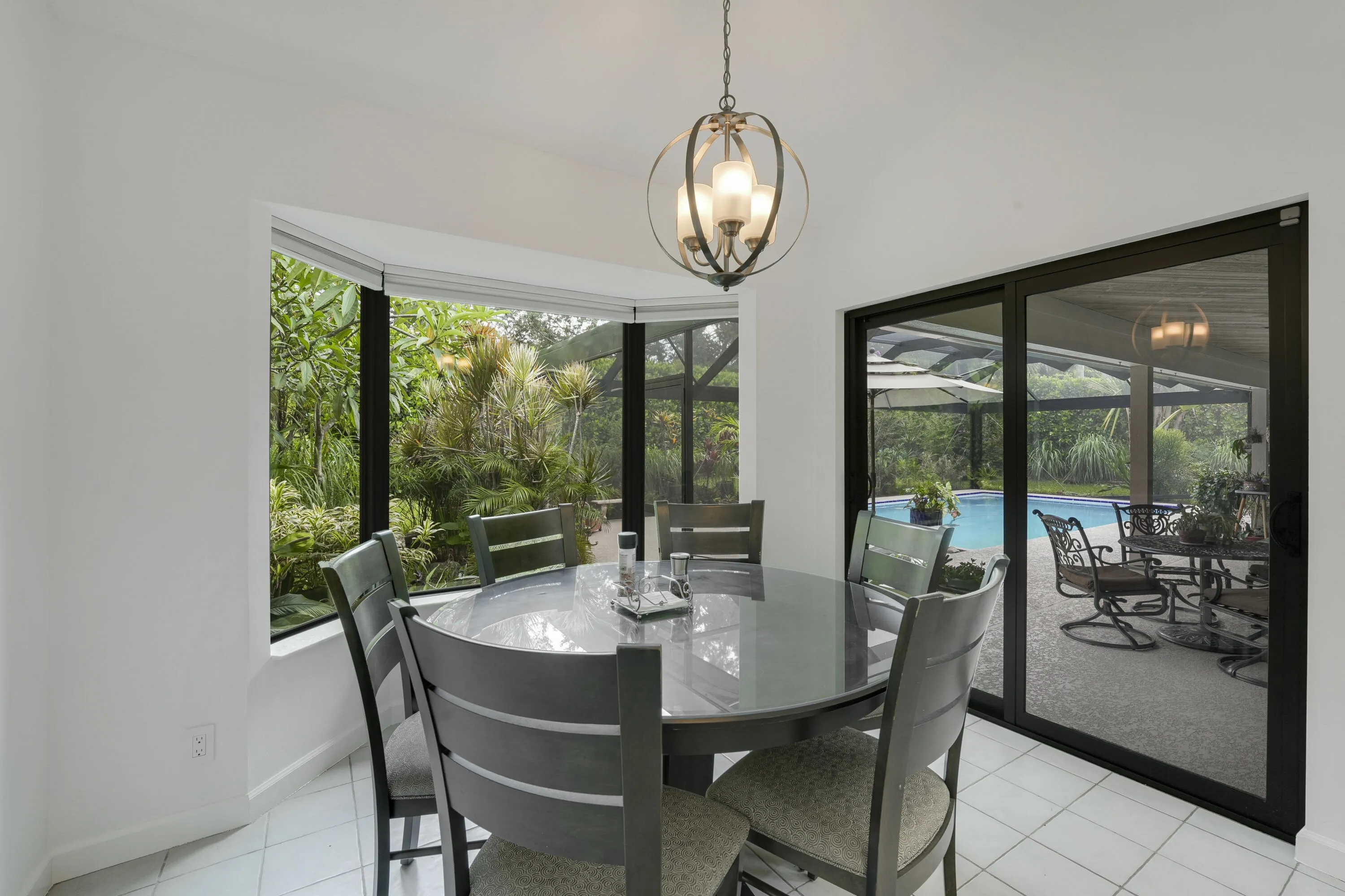Open dining area surrounded by windows and sliding doors, offering beautiful views of the greenery and screened patio.