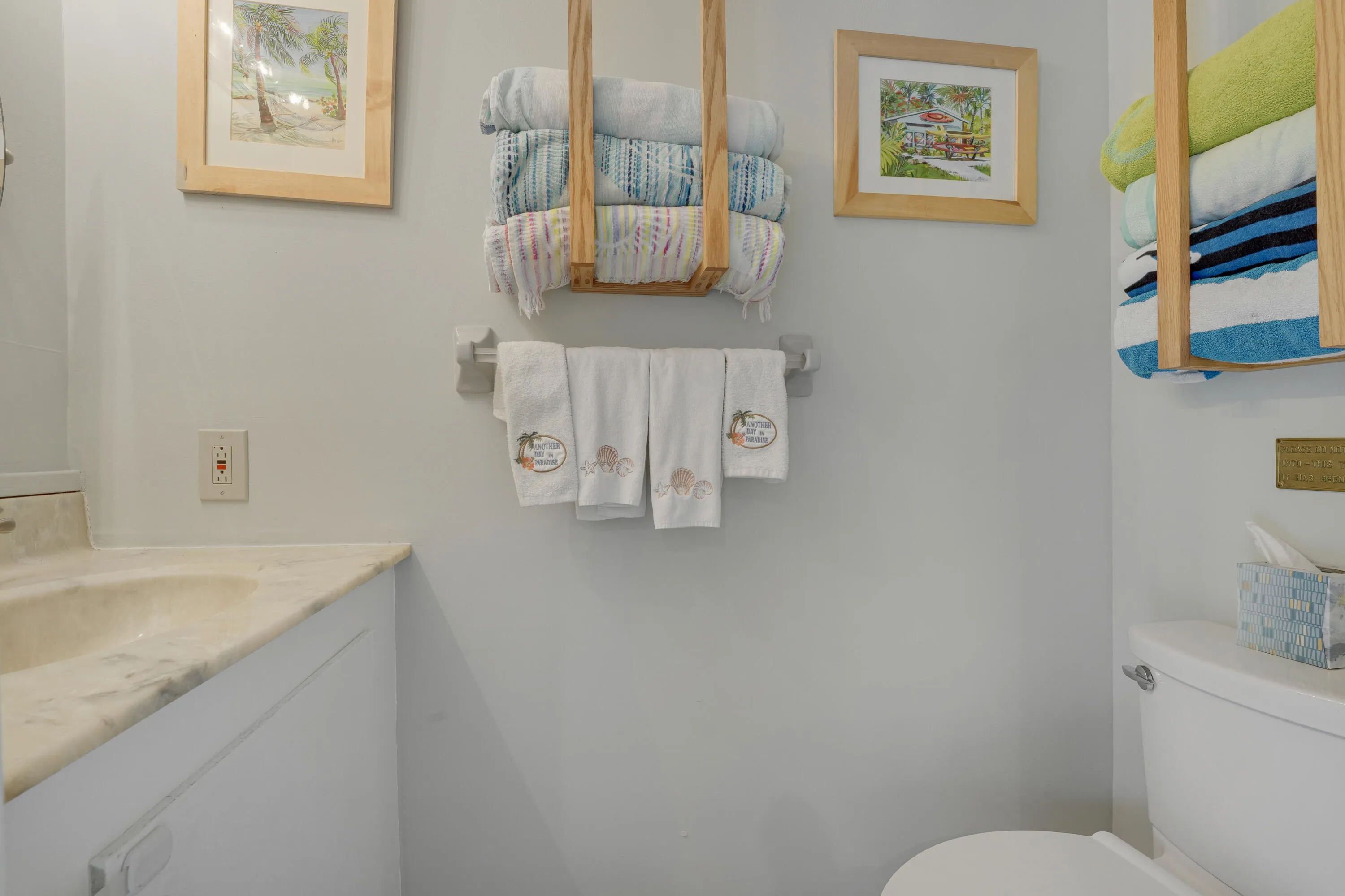 Clean and organized half bath featuring ample towel storage and neutral finishes — ideal for guests and poolside use.