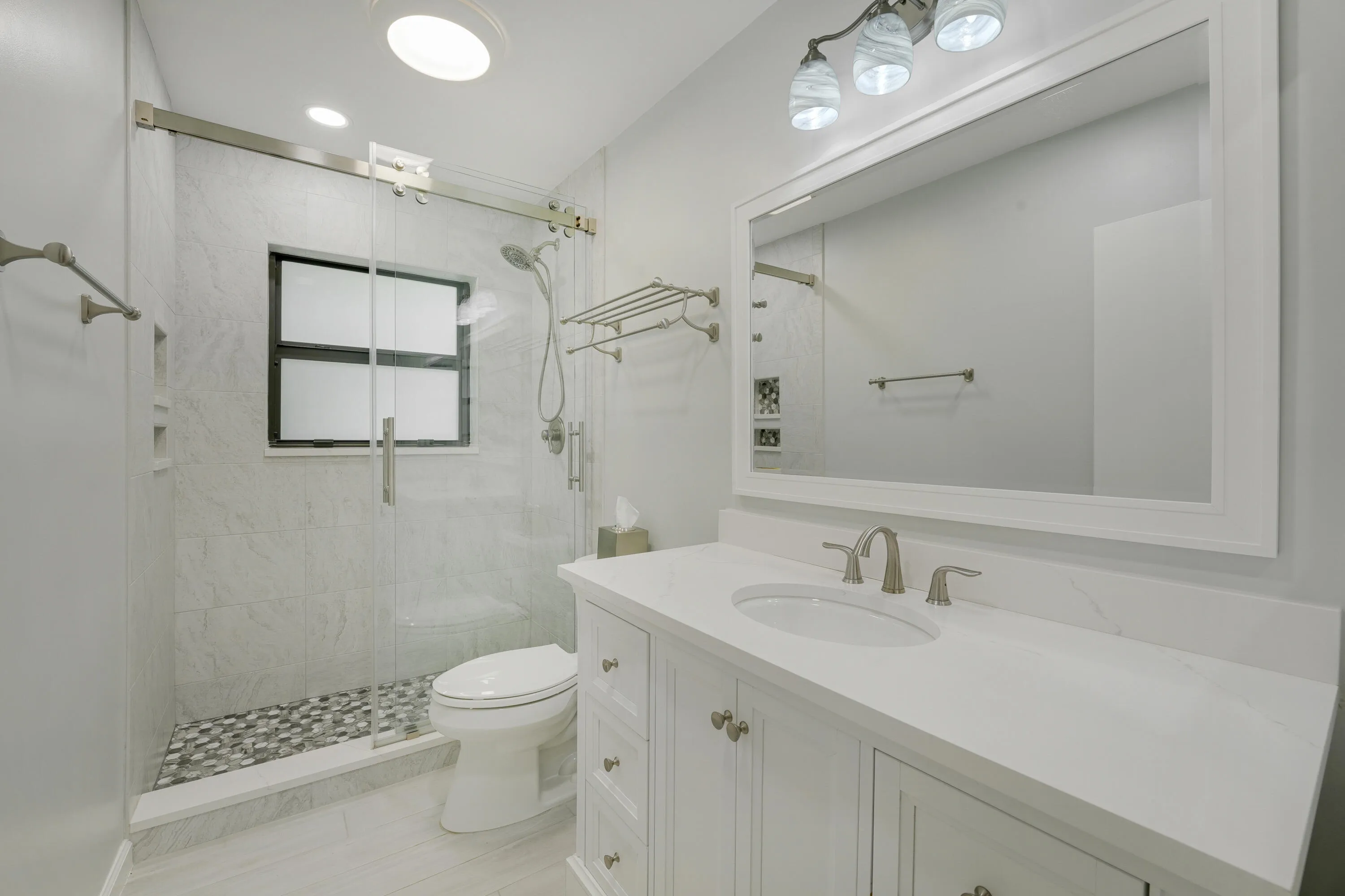 Beautifully updated guest bath featuring a sleek vanity, frameless glass shower, and modern tile finishes.