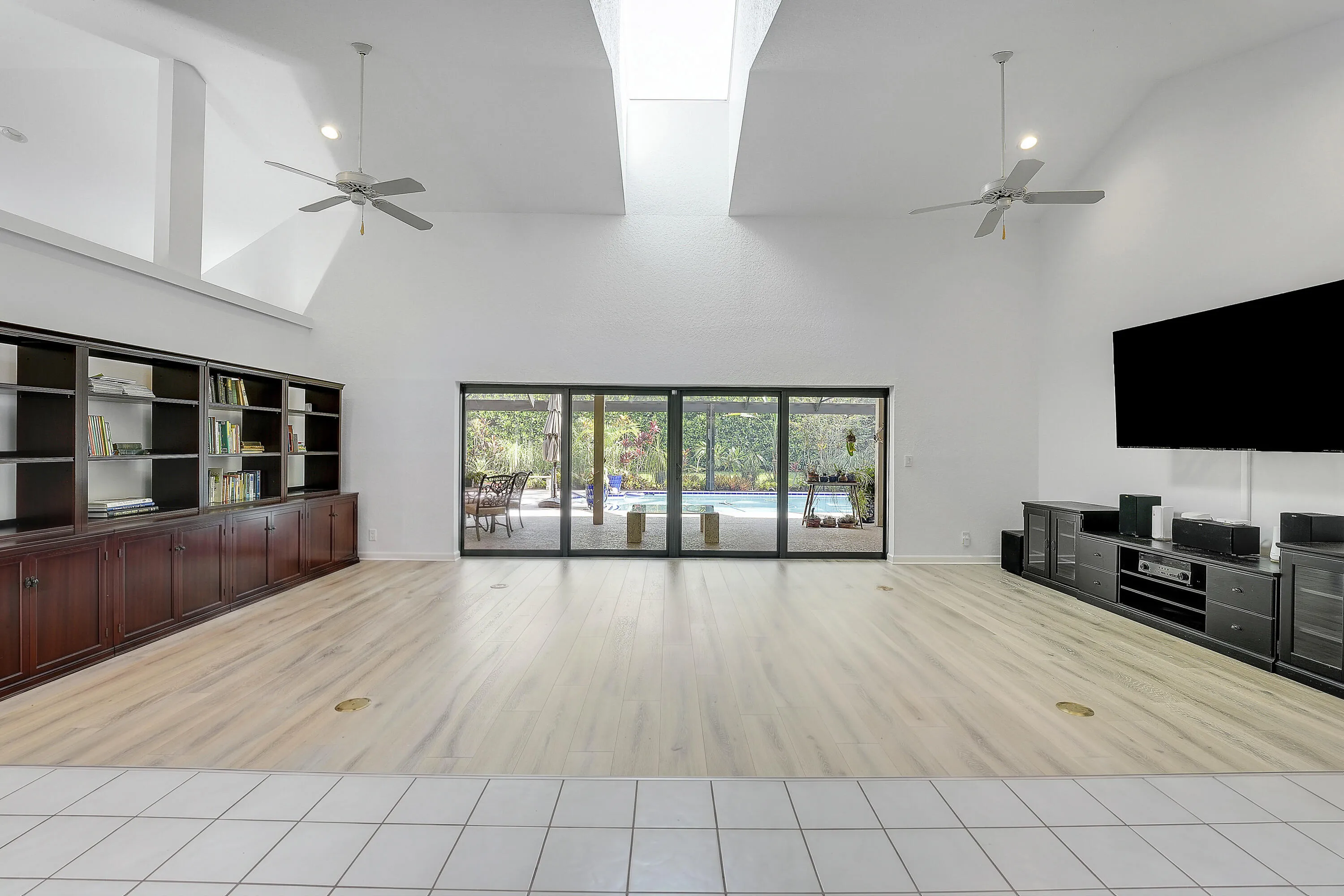 Front entry to a spacious great room featuring vaulted ceilings, abundant natural light, and seamless views of the pool and lush backyard.
