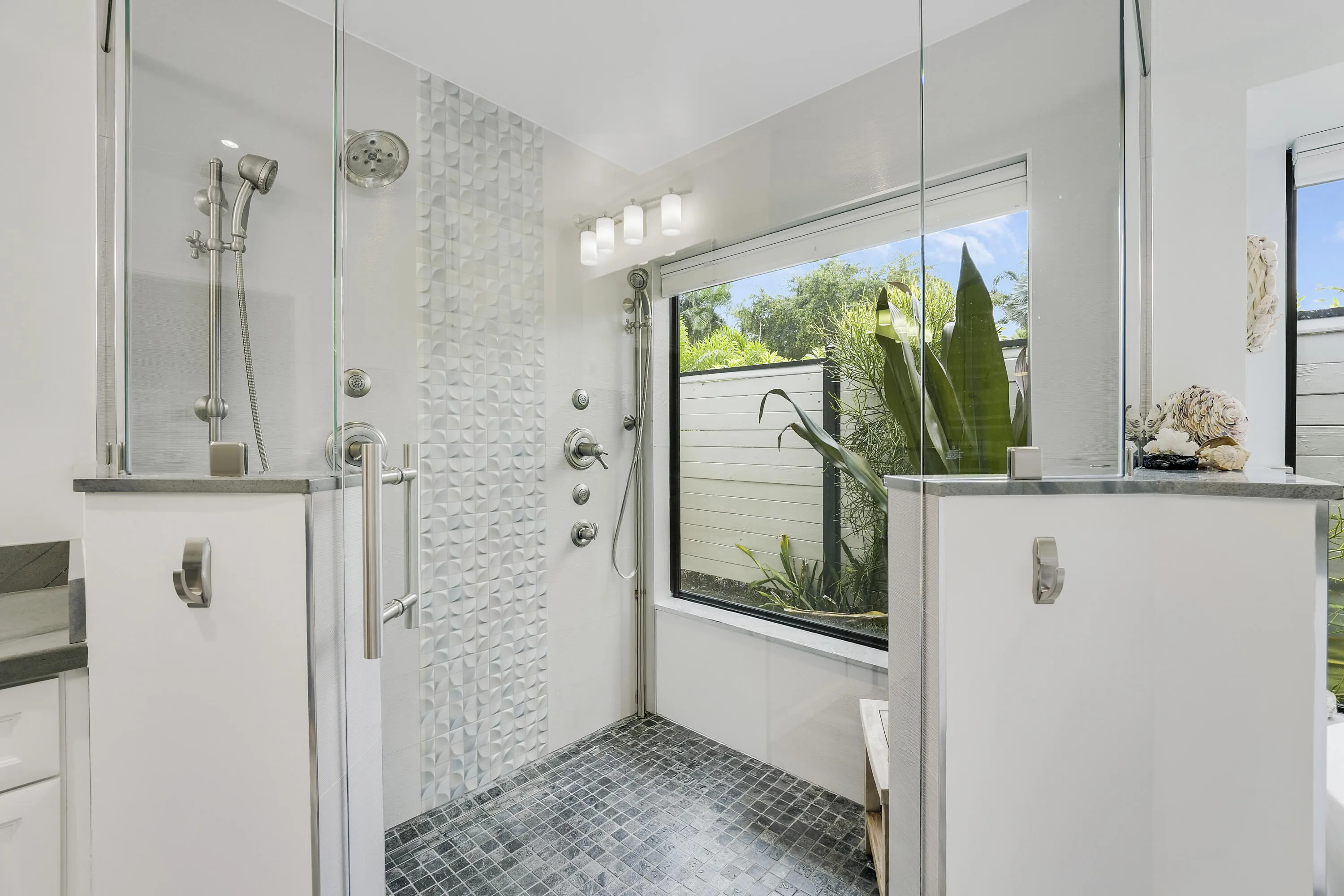 Spacious glassenclosed shower with dual showerheads, modern tile accents, and abundant natural light.