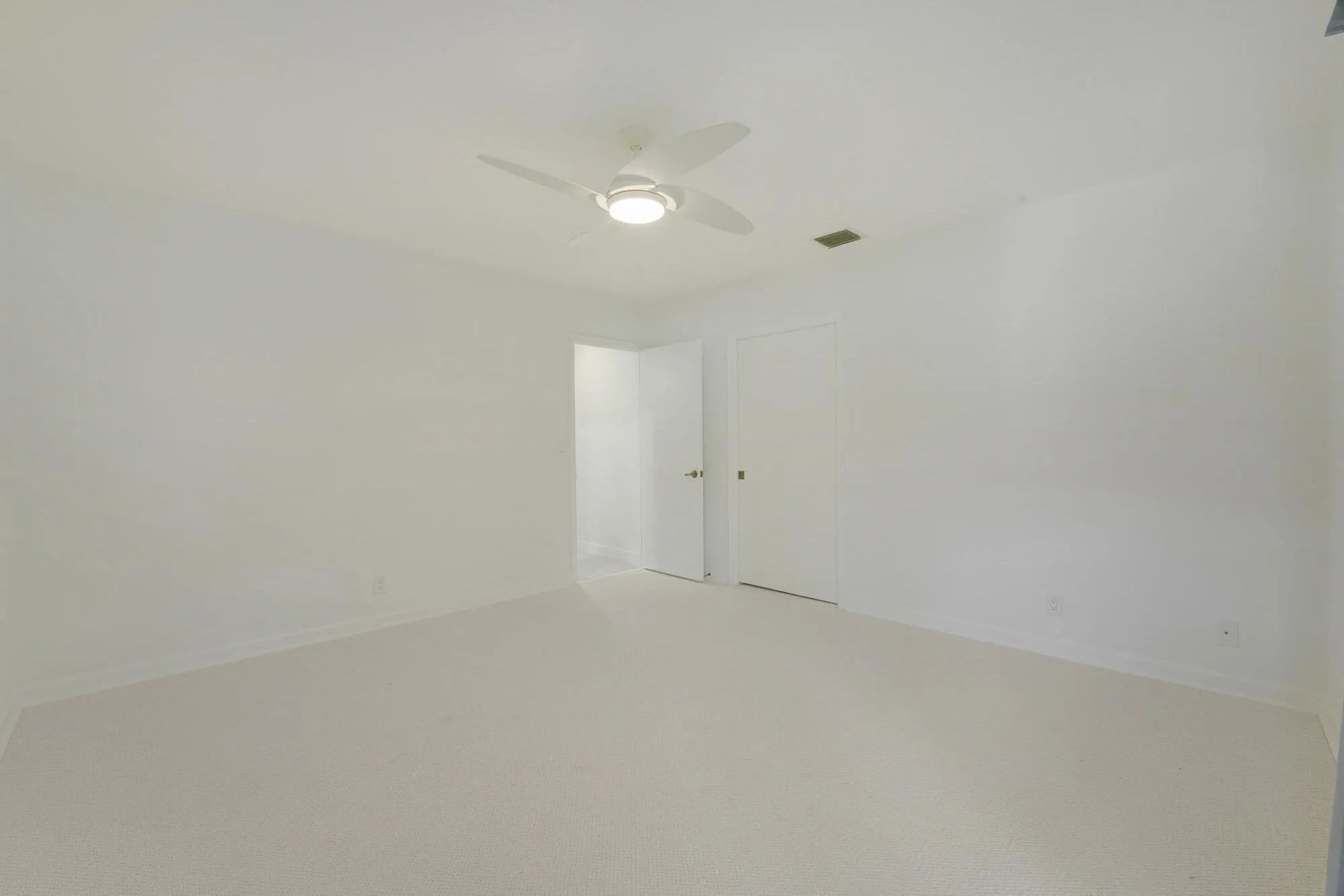 Spacious guest bedroom with new carpeting, Custom Elfa® Closet System, neutral finishes and natural light