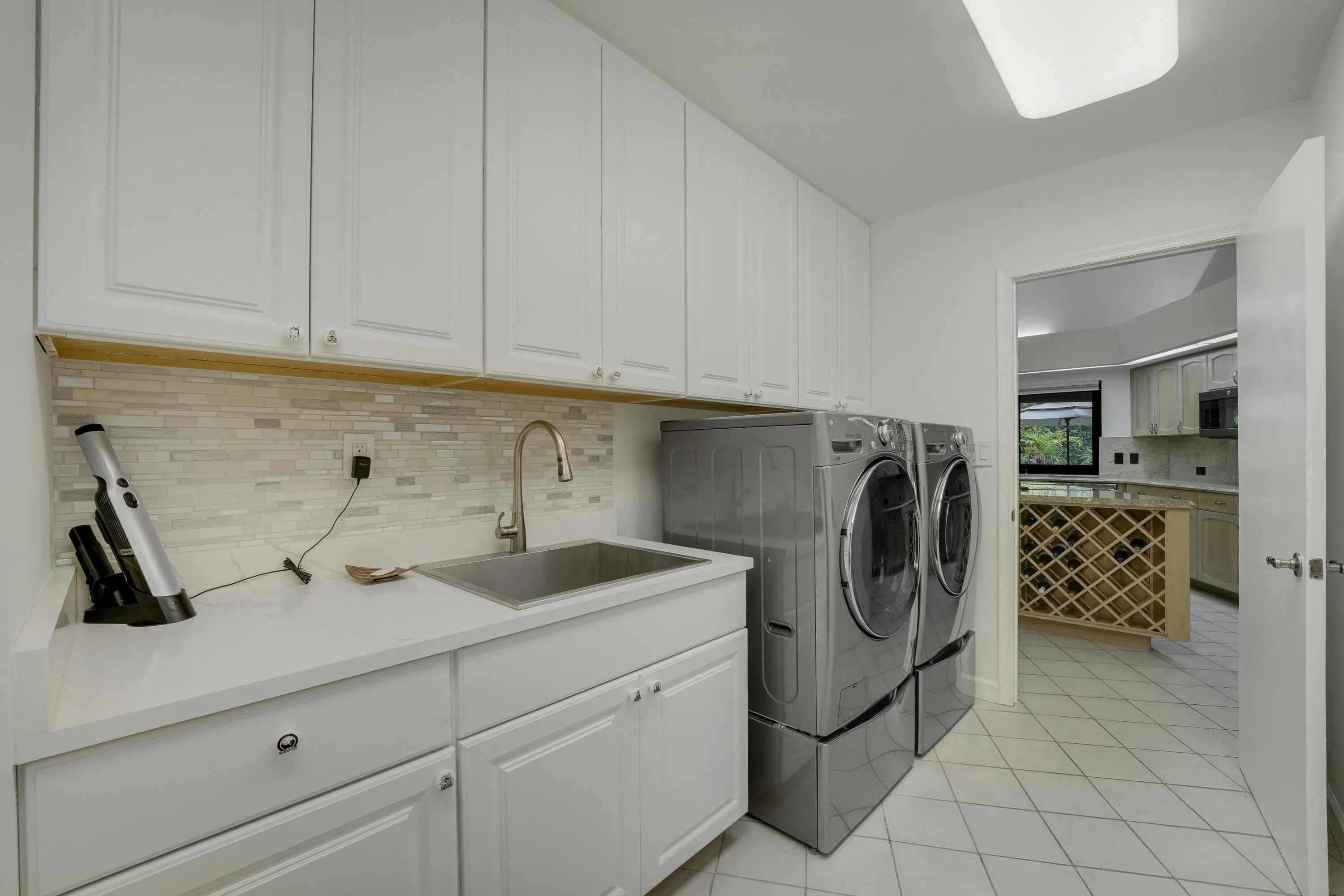 Modern Laundry Room With BuiltIn Utility Basin
Bright and wellappointed laundry room featuring extensive cabinetry, a spacious countertop with sink, front load appliances, and a convenient built-in utility/mop basin for added functionality.