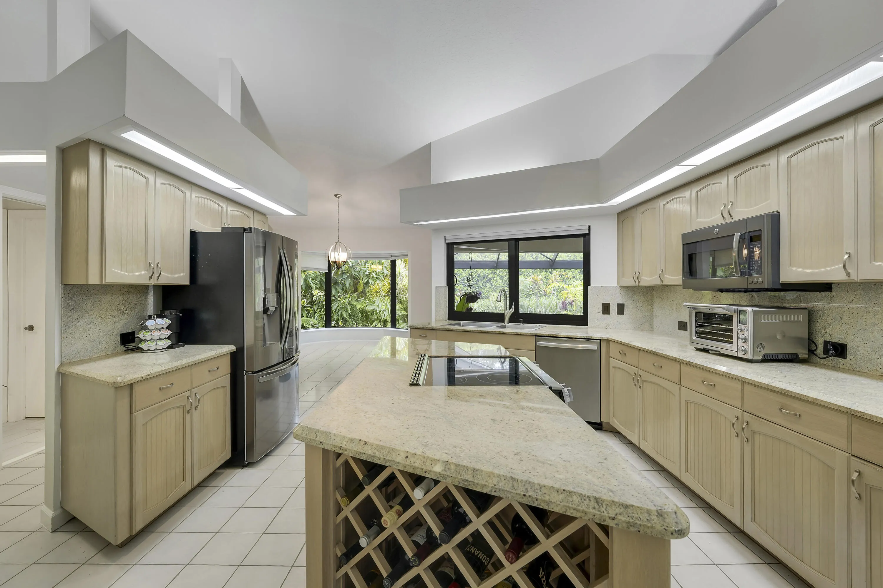 Light filled kitchen with extensive cabinetry, granite counters, stainless appliances, and a functional center island.